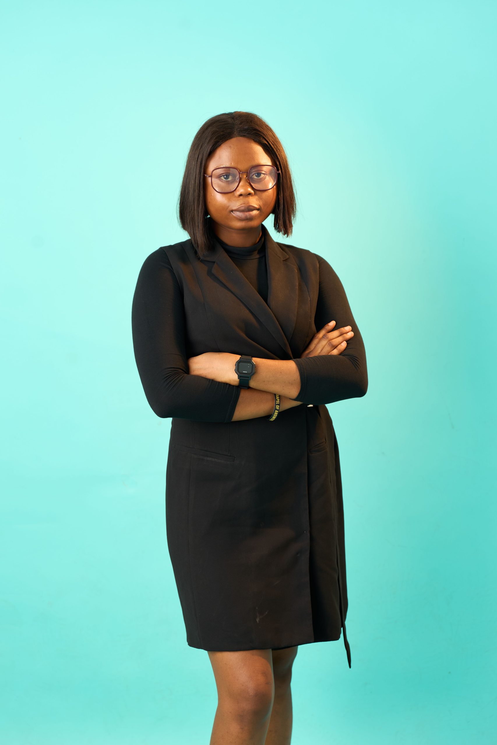 Portrait of a confident African woman in formal attire against a turquoise background.